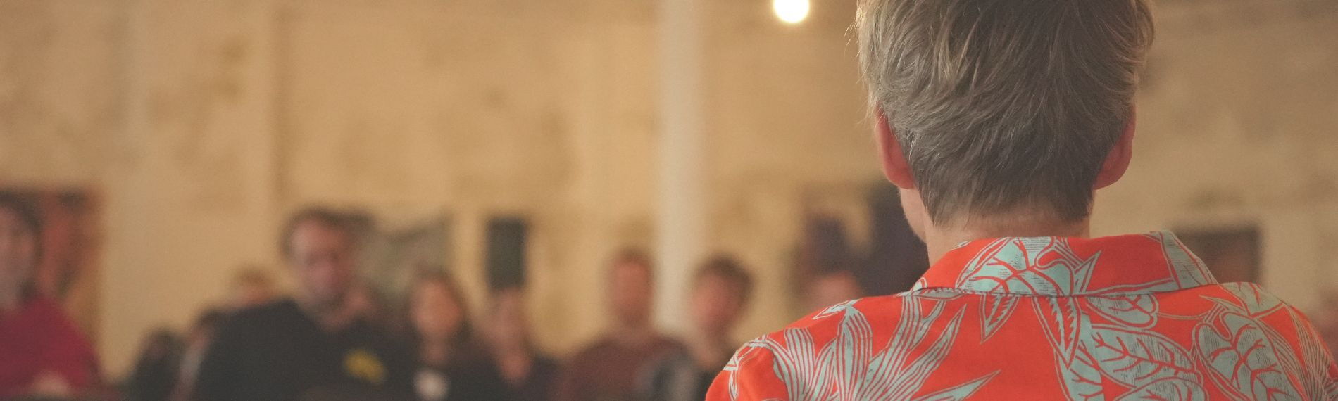 Rückansicht einer Person mit kurzen Haaren, die einen Vortrag hält