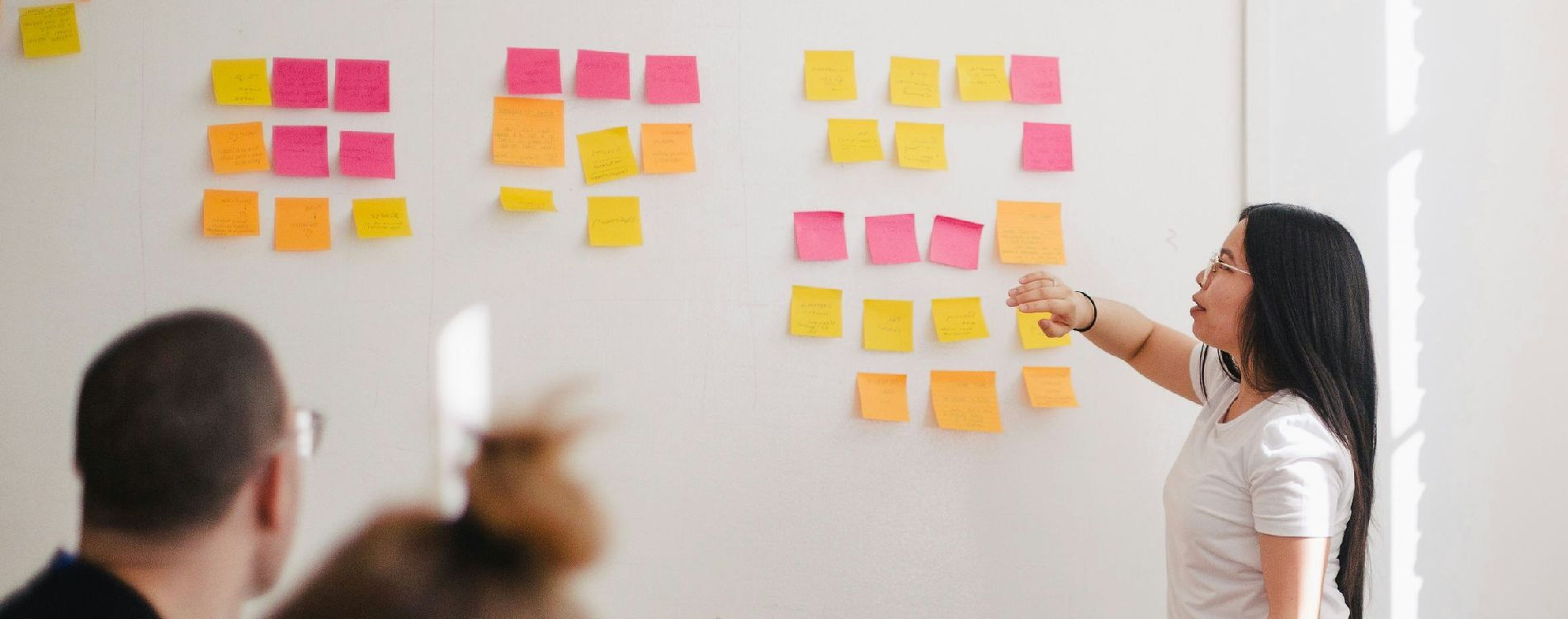 Person zeigt in einem Workshop auf verschiedenfarbige Notizzettel