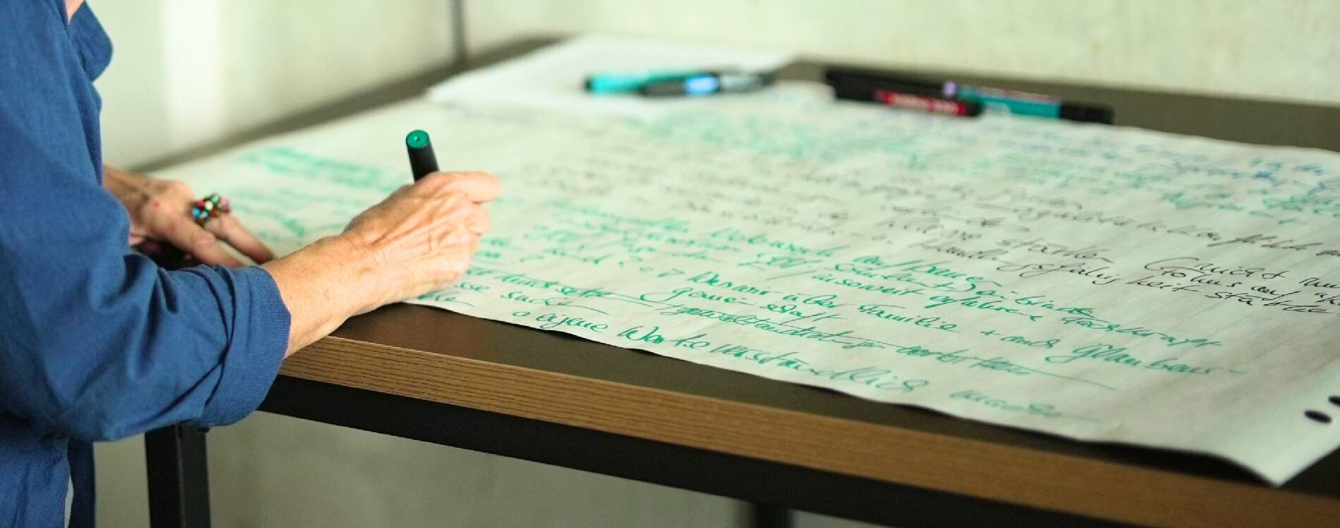 Person schreibt auf ein Flipchart-Papier