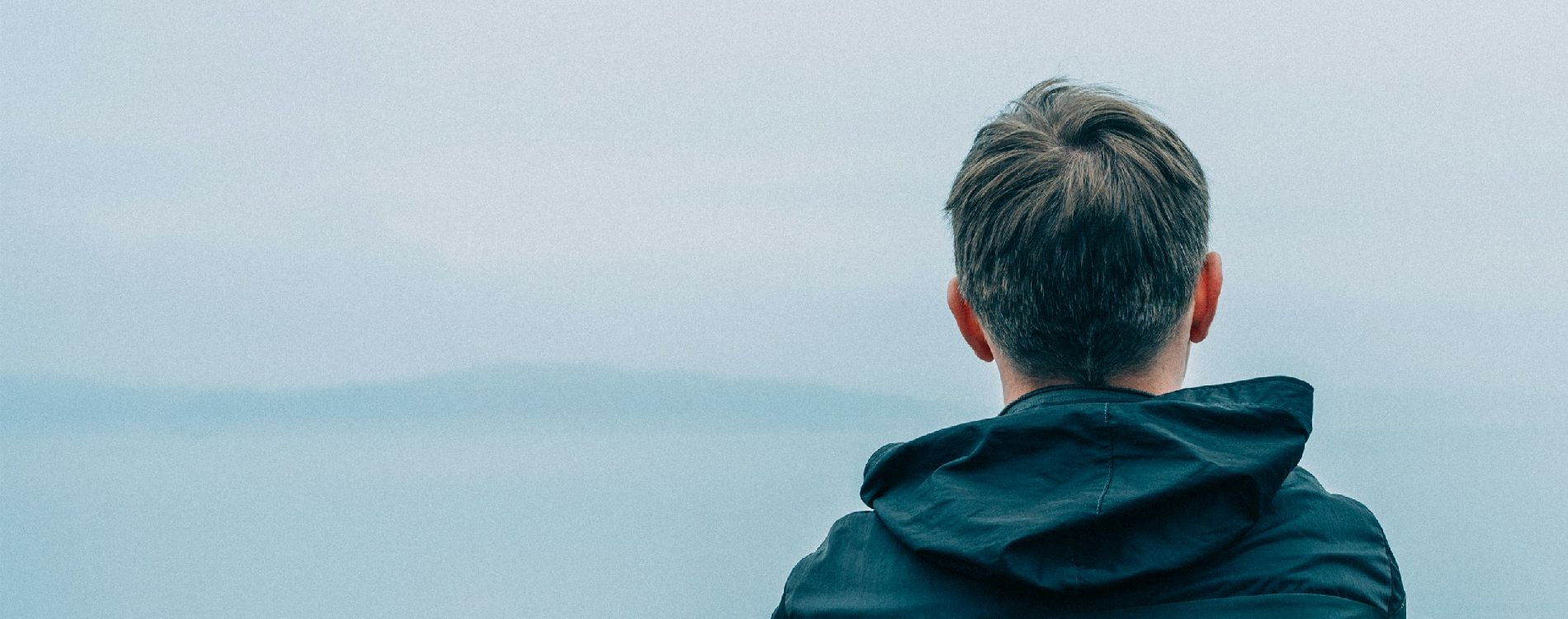 Junge Person vor einer vernebelten Landschaft